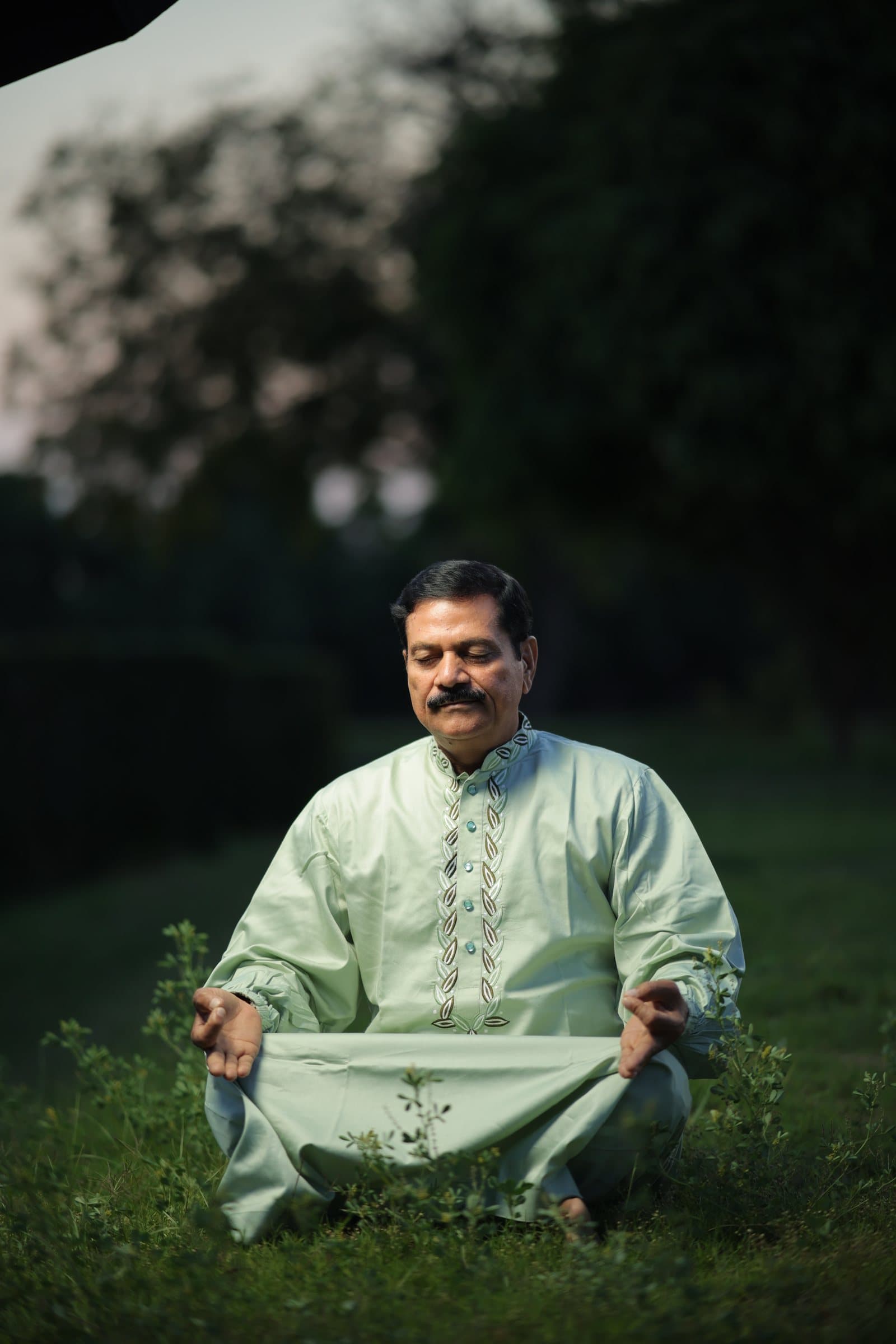 Anando sitting in meditation on the grass