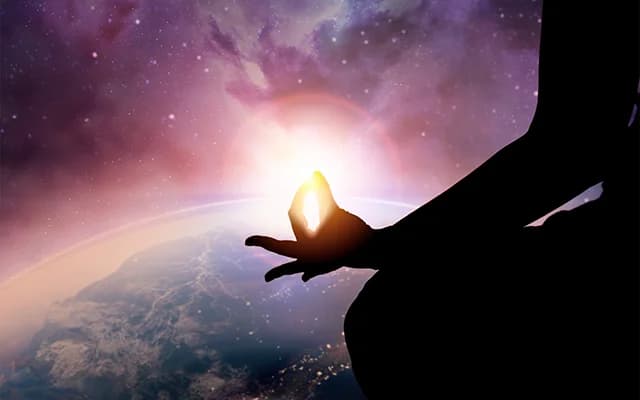 A meditating hand held against a glowing galaxy